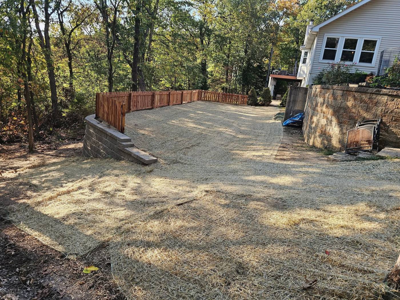 Retaining wall with a wood fence along a new gravel yard