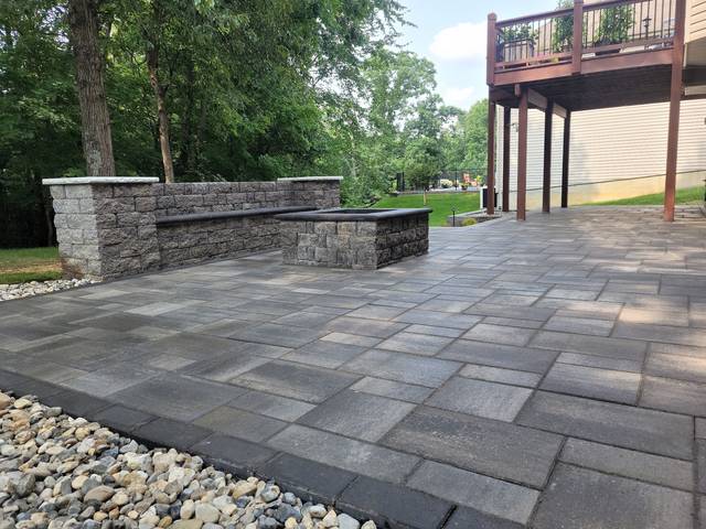 Paver patio with a seating wall and a rock edge